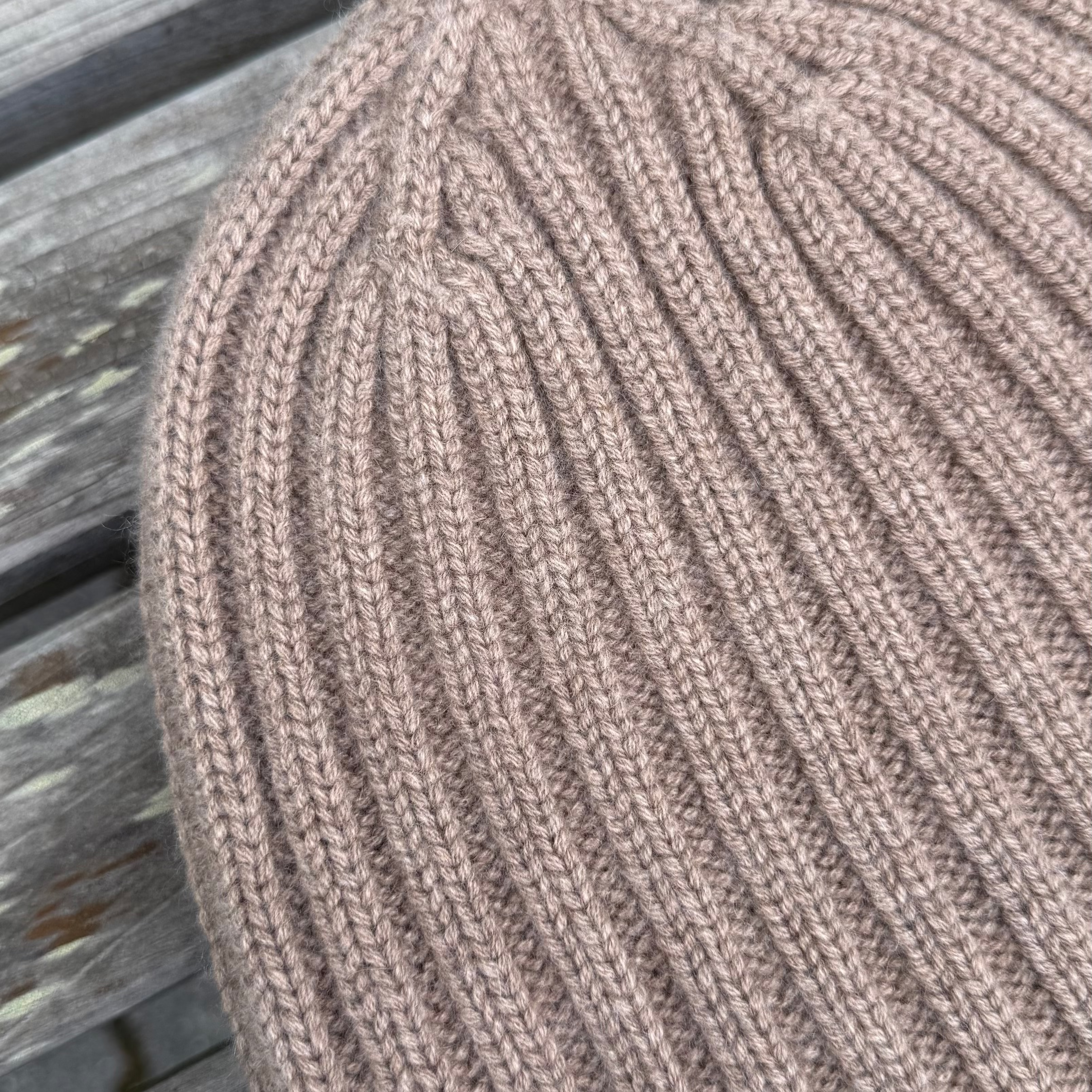 Close-up of a brown knitted beanie on a wooden surface