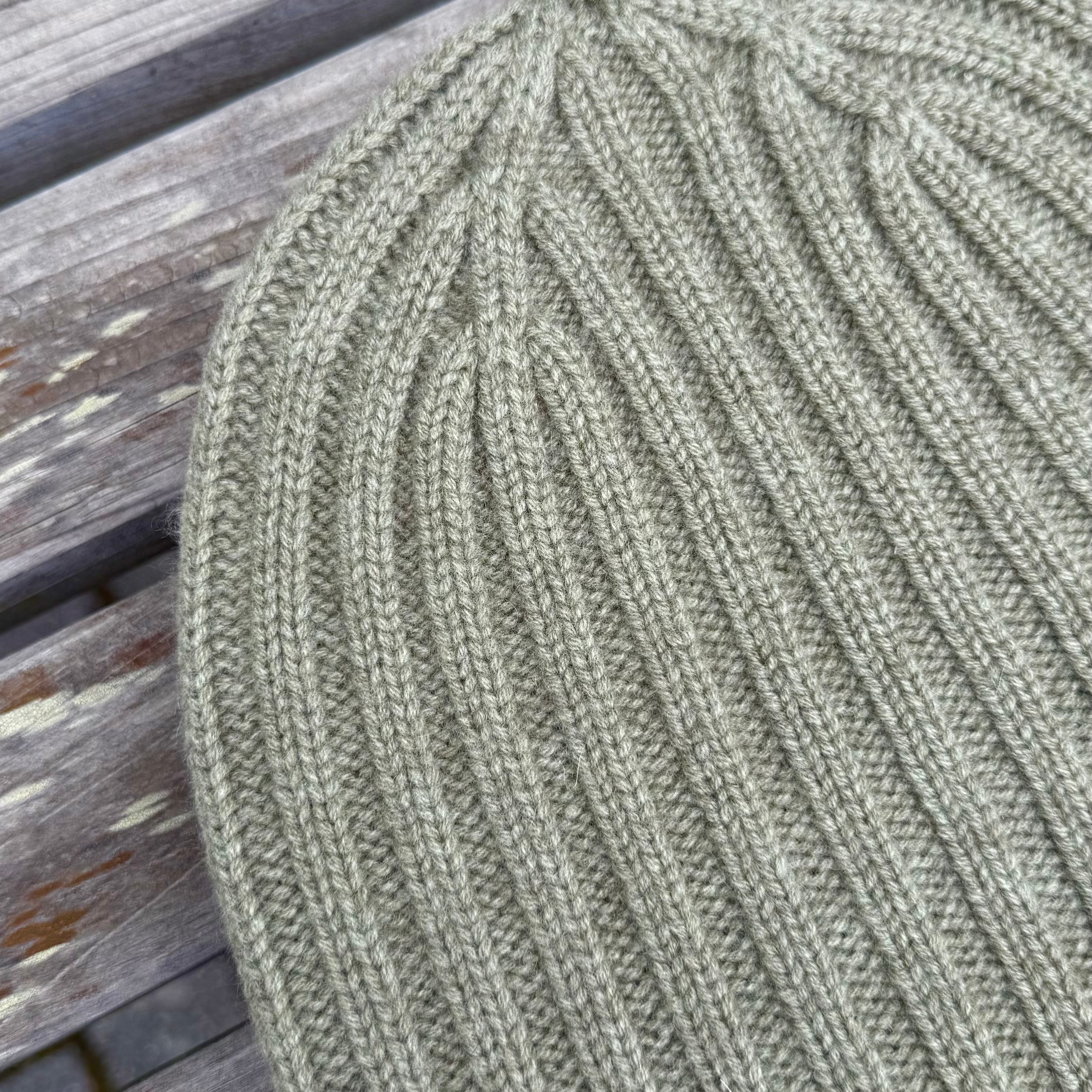 Close-up of a green knitted beanie on a wooden surface