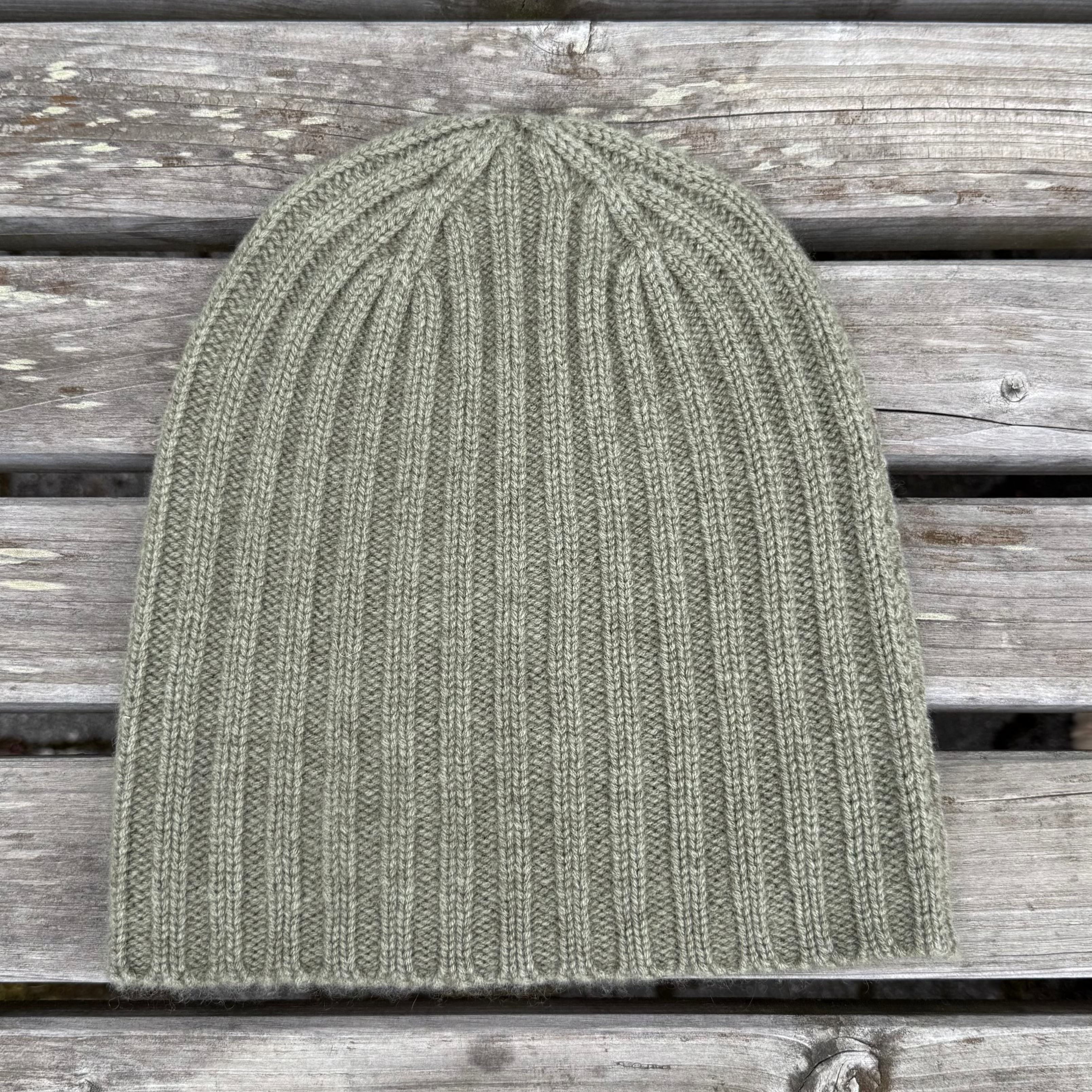 Green knit beanie on a wooden surface