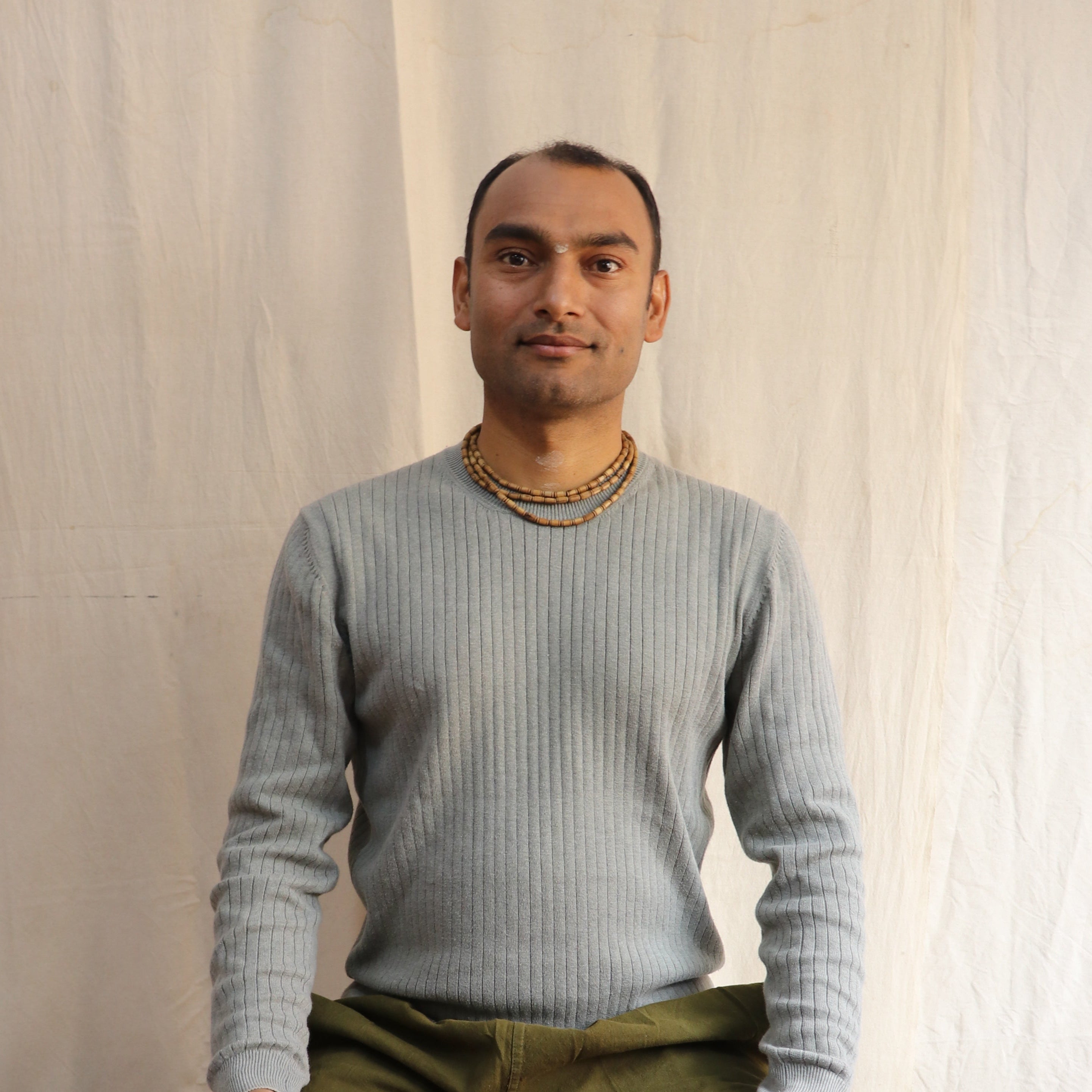 Man is sitting for a portrait while wearing handmade clothing made from cashmere.